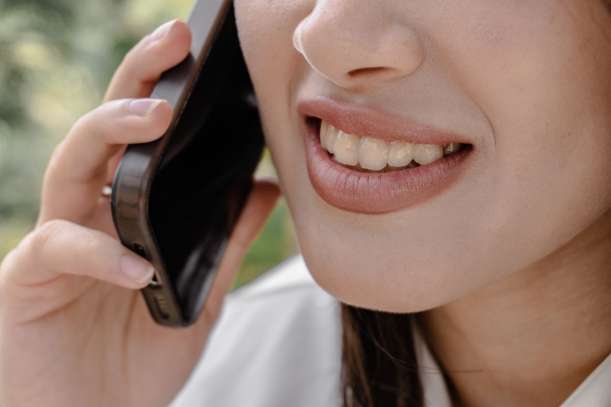 Person smiling warmly during a phone call