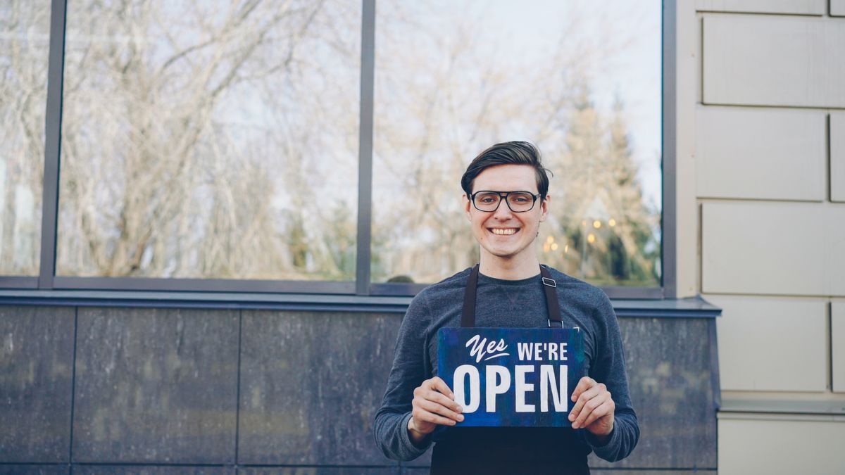 Smiling business owner holding an open sign