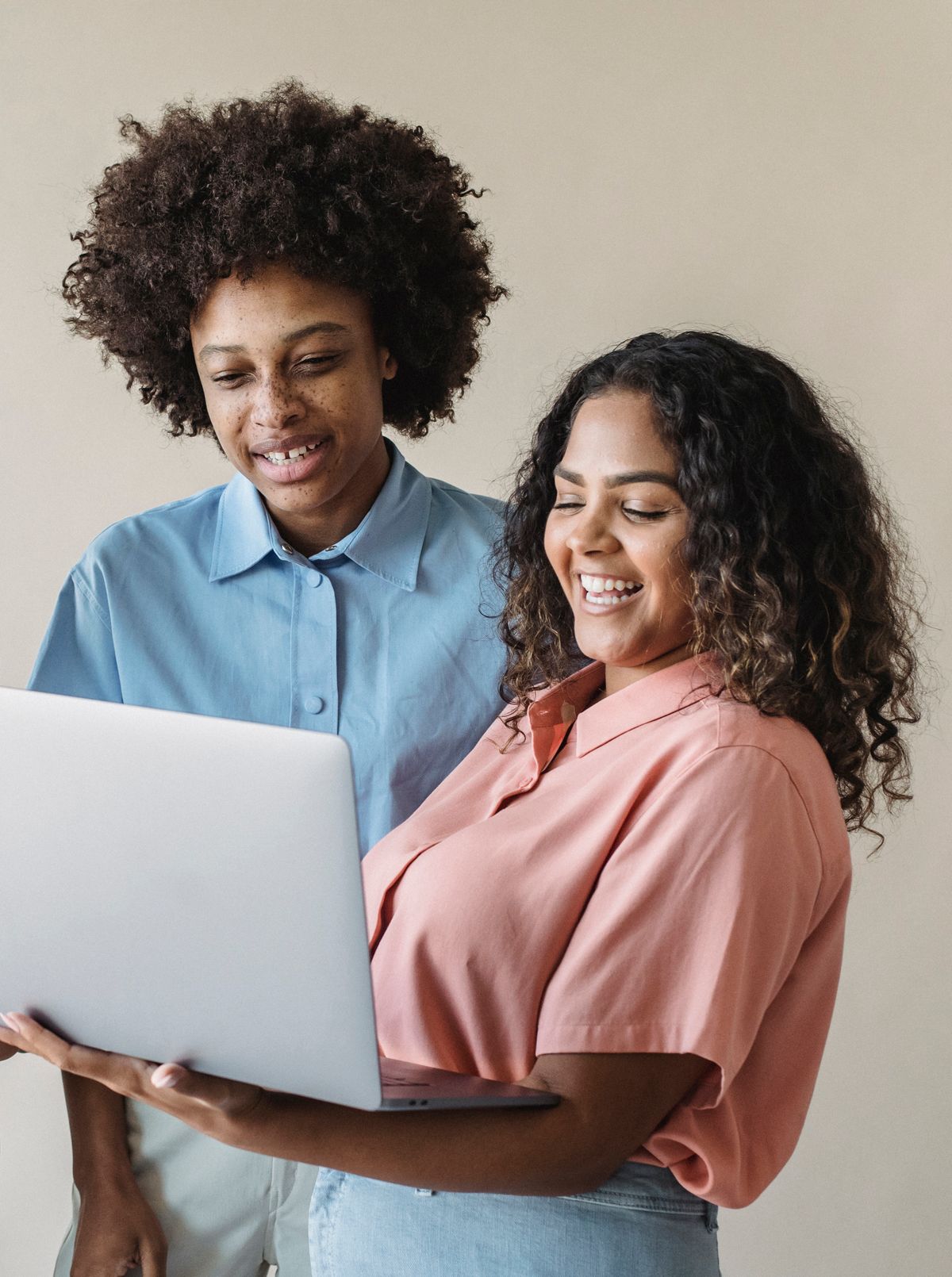 Two people smiling while looking at a laptop together